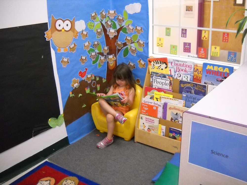 Child sitting in yellow chair reading a book
