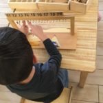 Child working in Math area with Teen Bead Stair to practice associating quantities to the abstract numbers