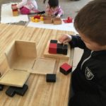 Several children working with sensorial materials during work cycle including Trinomial Cube, Knobless Cylinders and Sound Cylinders